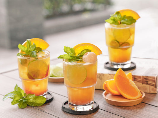 Three clear glasses of iced tea with lemon slices and mint leaves