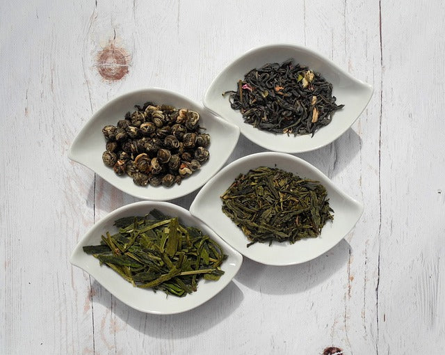 Four oval shaped bowls, each containing a different type of looseleaf tea
