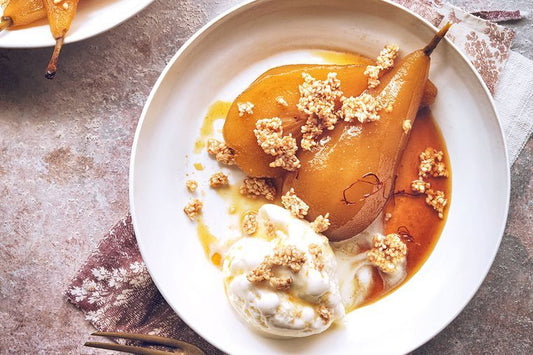 a white bowl of golden poached pears with ice cream