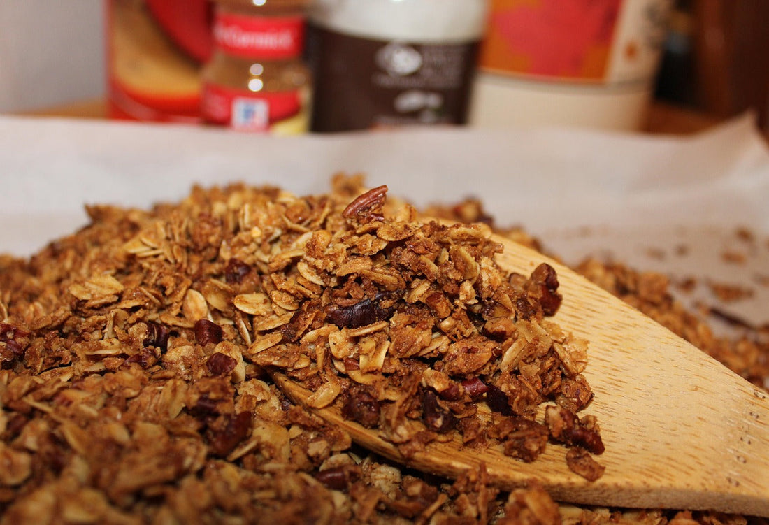 A pile of granola with a wooden spoon holding some of it