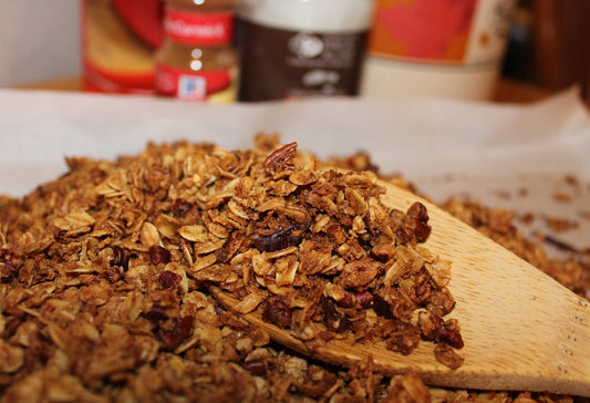 A pile of granola with a wooden spoon holding some of it