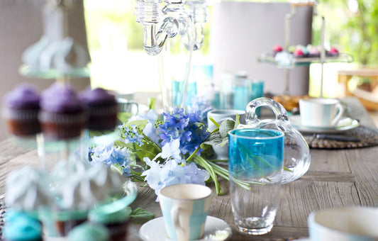 Image of a table setting with blue and white cups and glasses and blue flowers.