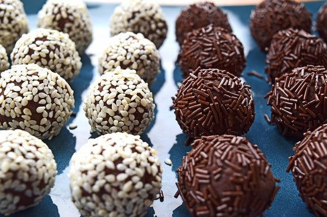 Rows of chocolate truffles with some coated in white sprinkles and some in chocolate sprinkles.